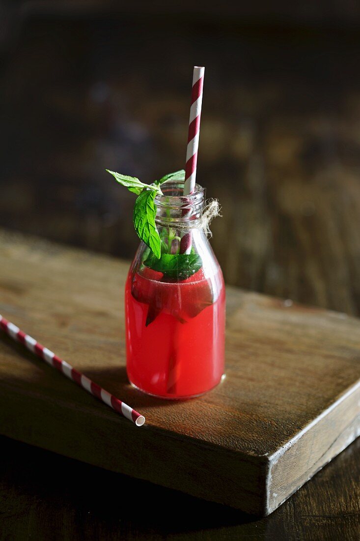 A bottle of watermelon juice with fresh mint