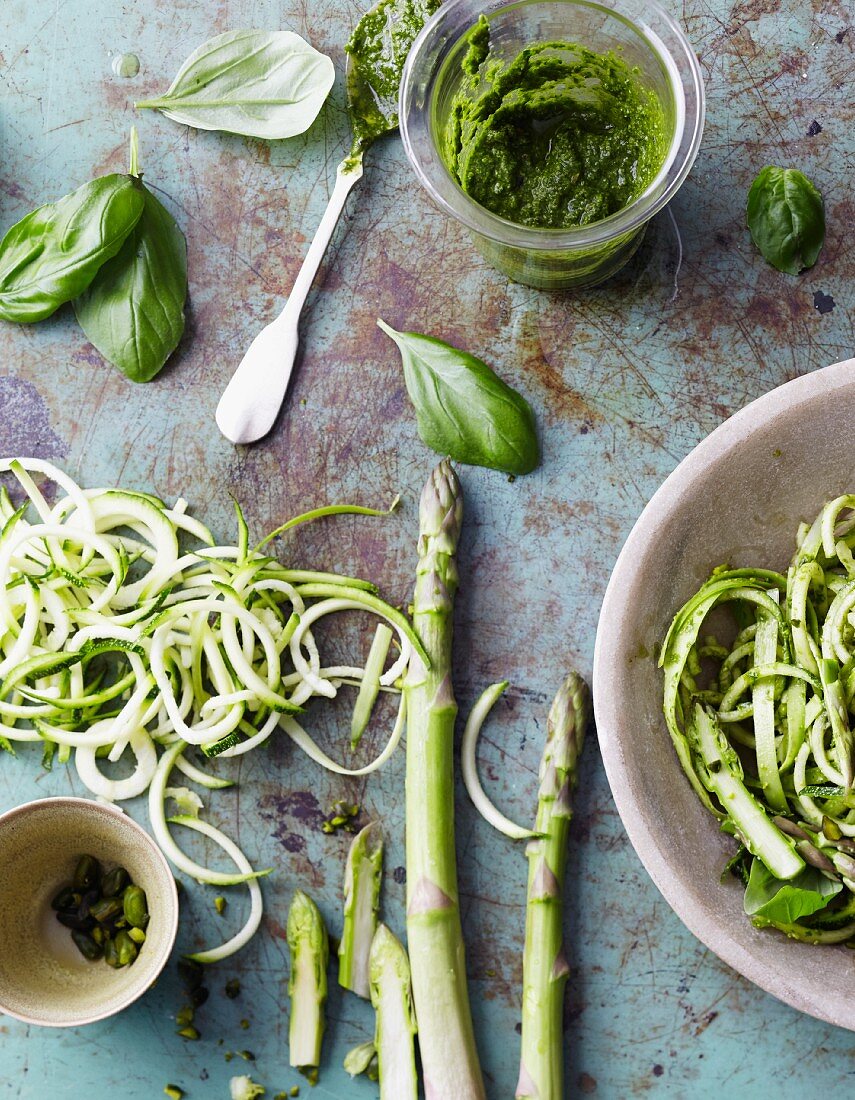 An arrangement of green asparagus, courgette, basil and pesto