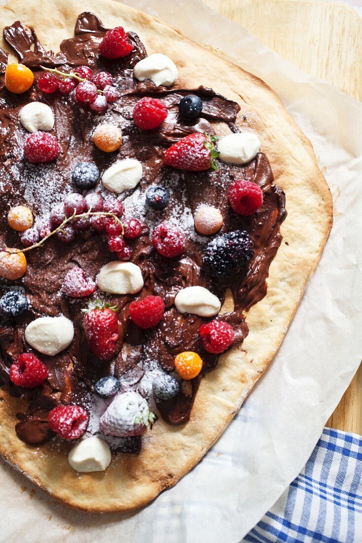 Fruit pizza with chocolate cream, berries and physalis