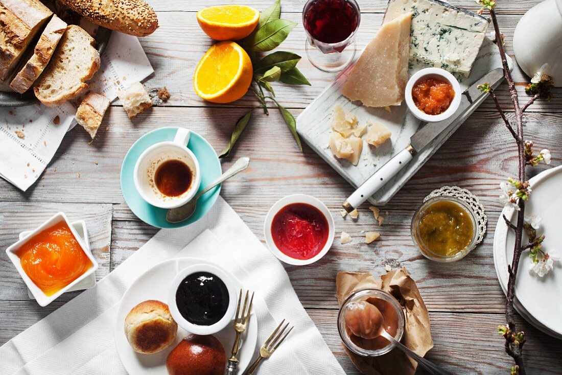 Verschiedene Marmeladen mit Käse, Brot und Getränken auf Holztisch