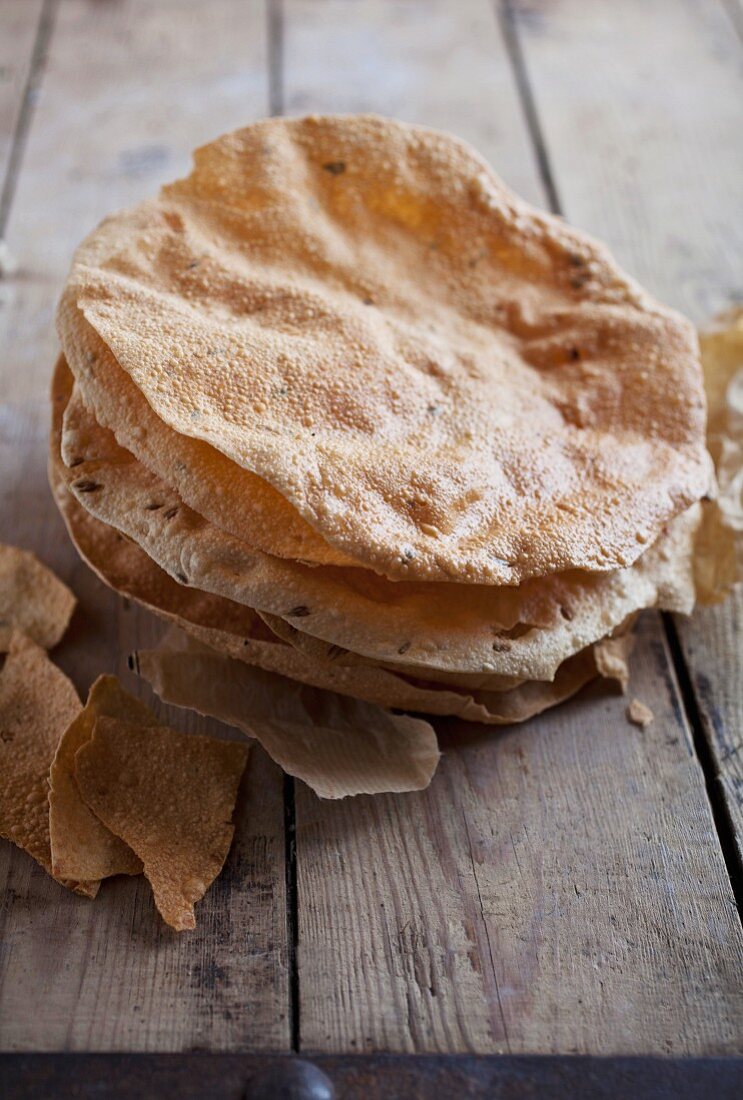 A stack of poppadoms on a wooden table