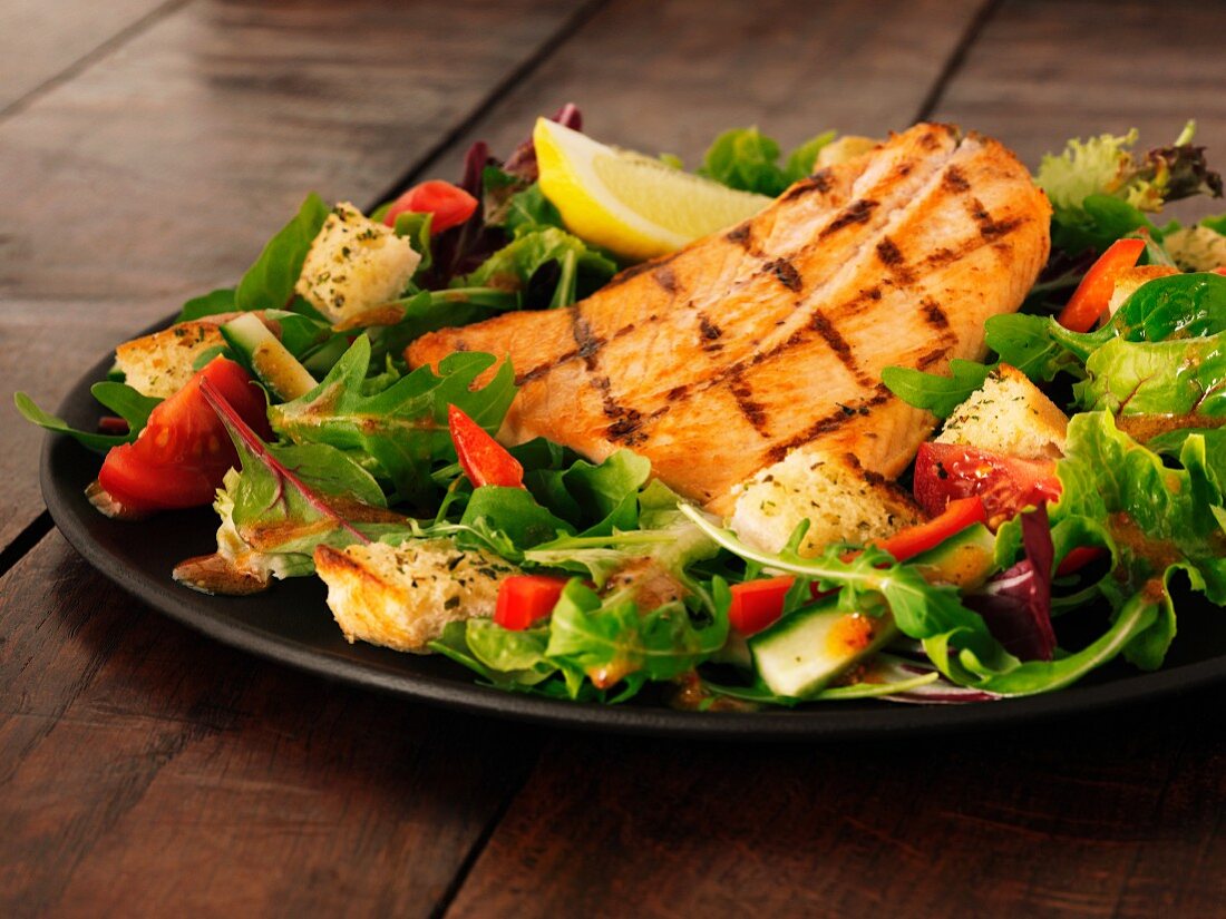 Salmon fillet on a bed of rocket with tomatoes and croutons