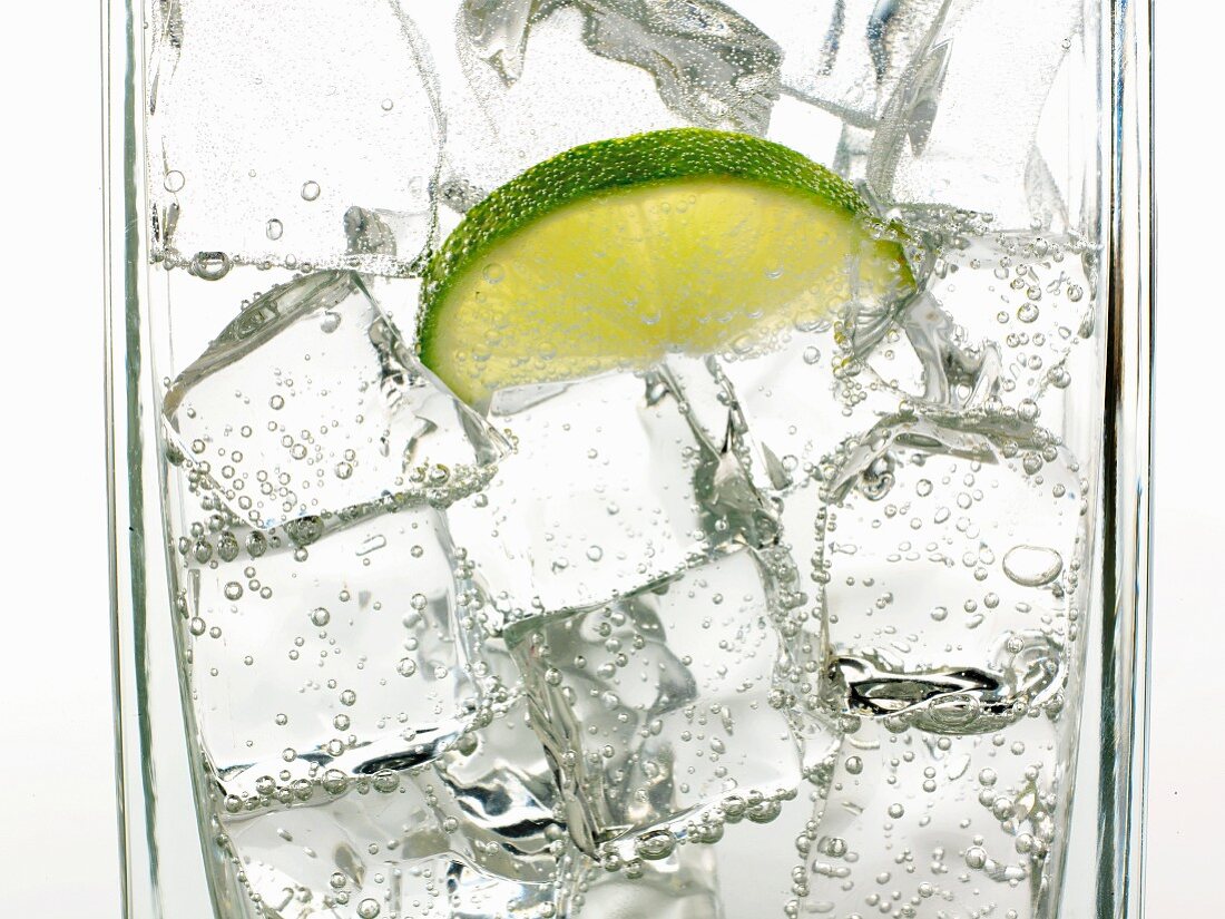 Mineralwasser mit Eiswürfeln und Limettenschnitz