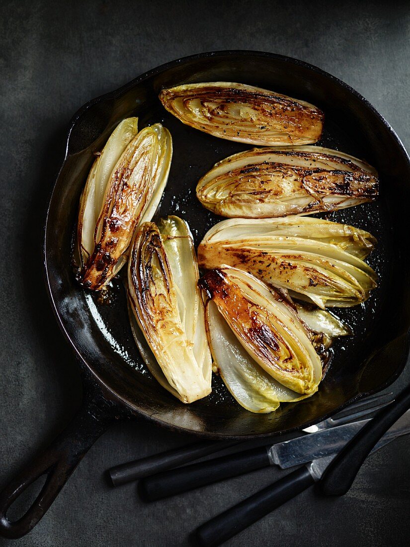 Fried chicory halves in a pan