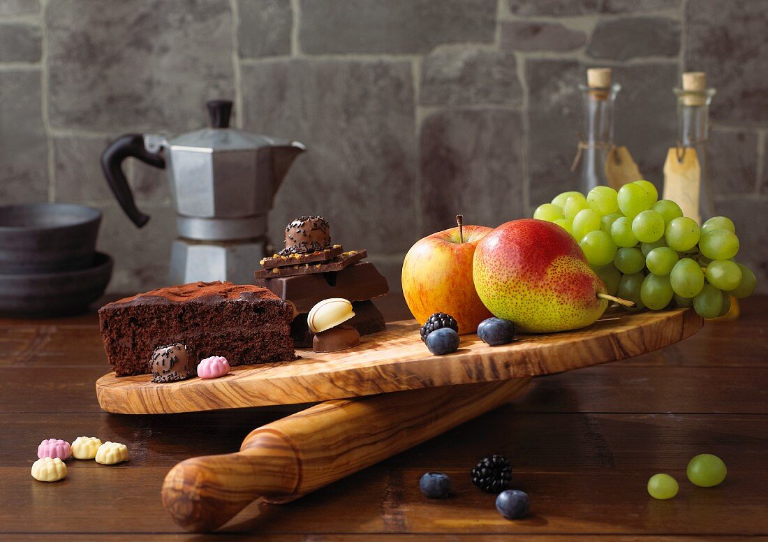 Chocolate cake and sweets on a chopping board being compared with fruit