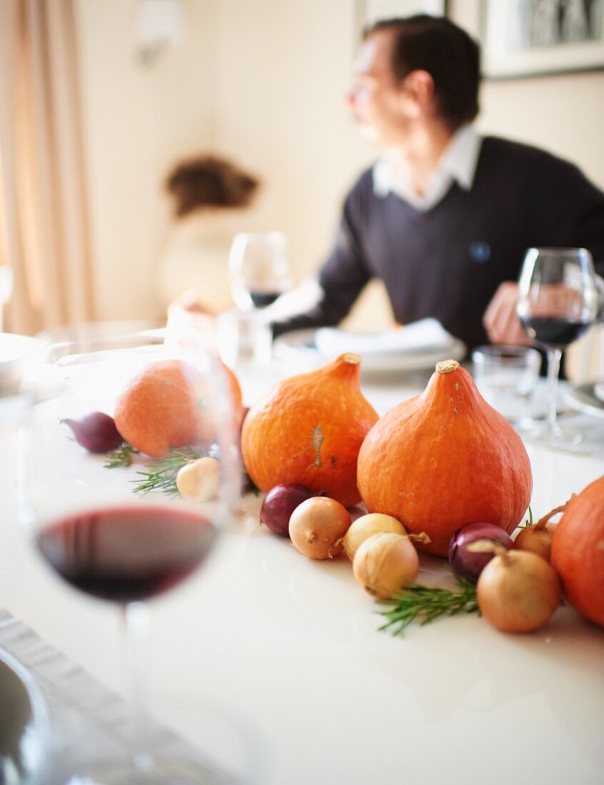 Gedeckter Tisch zu Thanksgiving mit Kürbisdeko und Zwiebeln