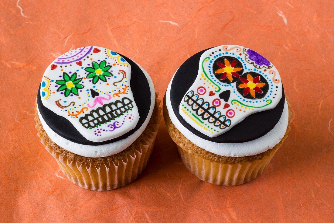 Two Halloween cupcakes decorated with skulls