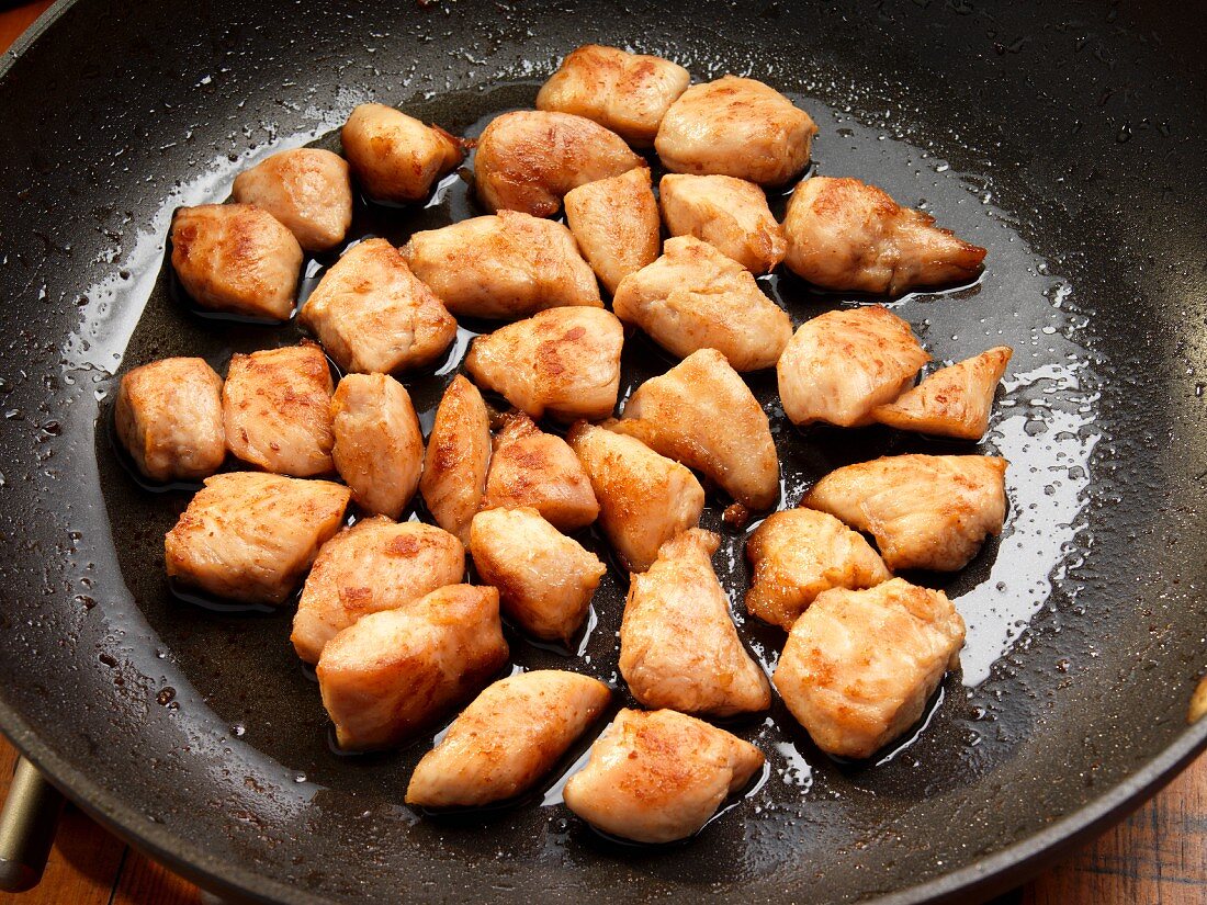 Flour-dusted chicken breast frying in a pan