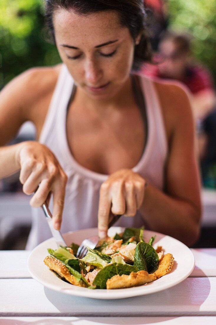 Frau isst Lachssalat im Gartenrestaurant