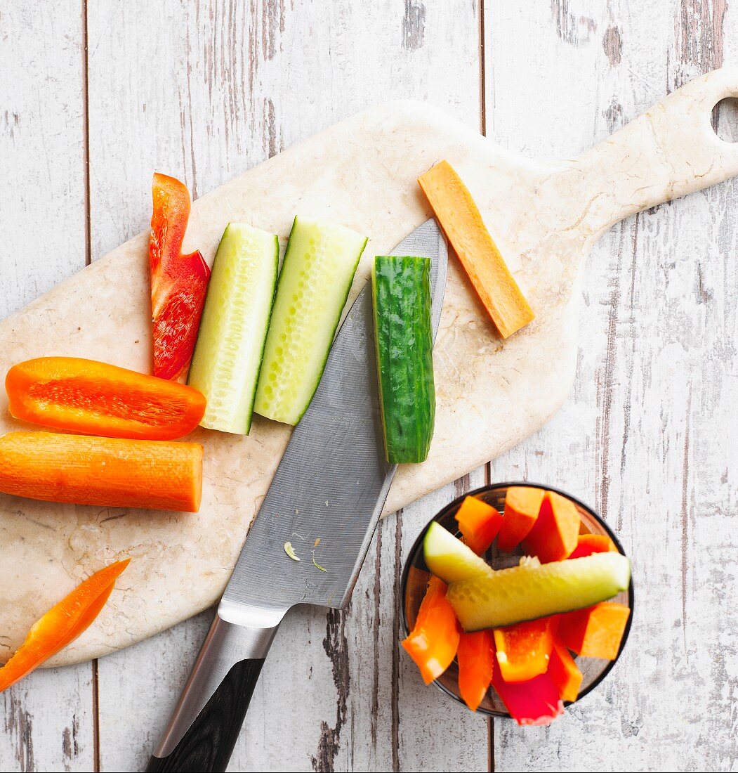 Raw vegetables with a knife on a chopping board