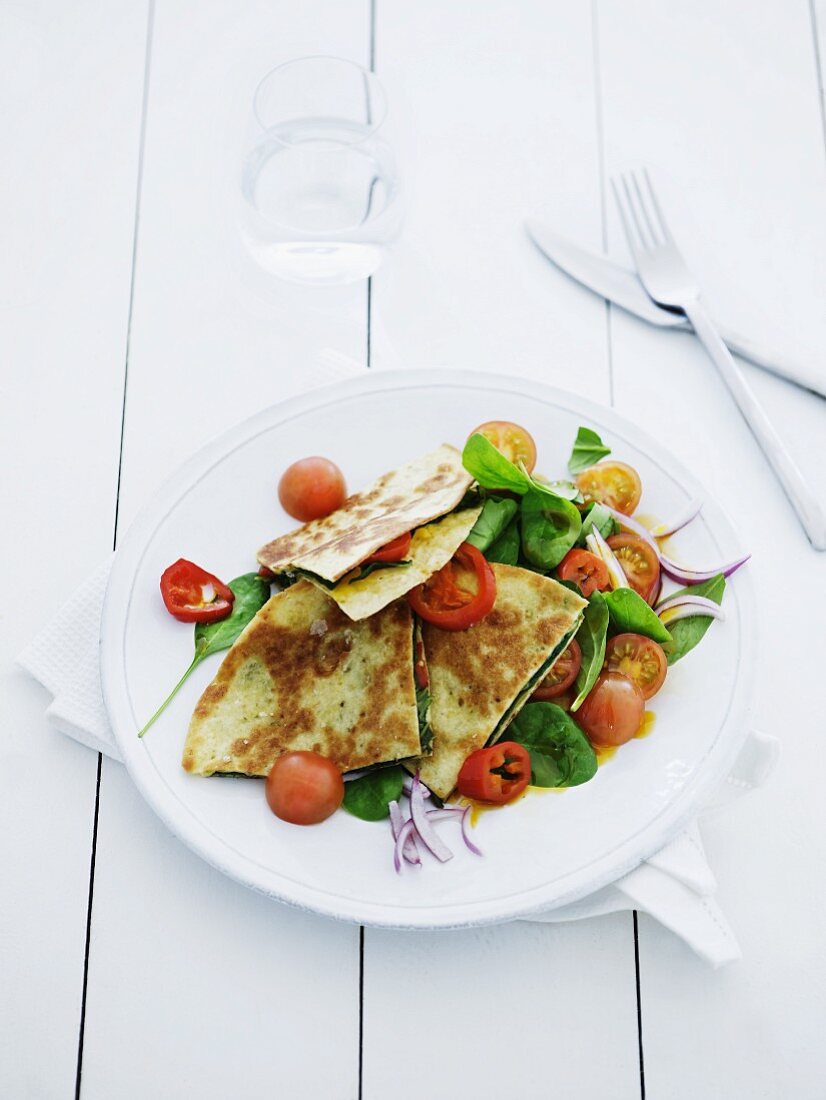 Pancakes filled with baby spinach and tomatoes