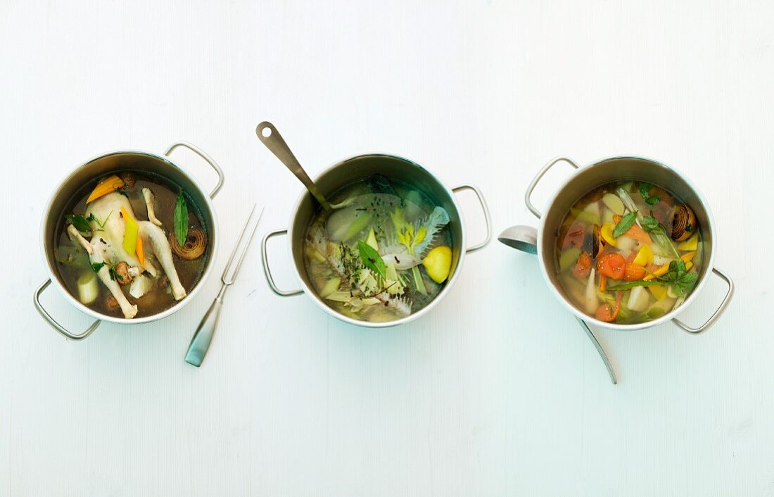 Chicken stock, fish stock and vegetable stock in saucepans