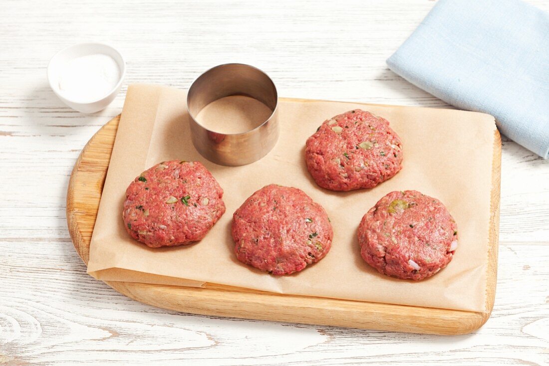 Raw burgers on a chopping board