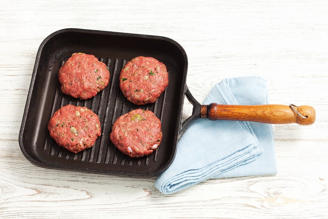 Raw burgers in a grill pan