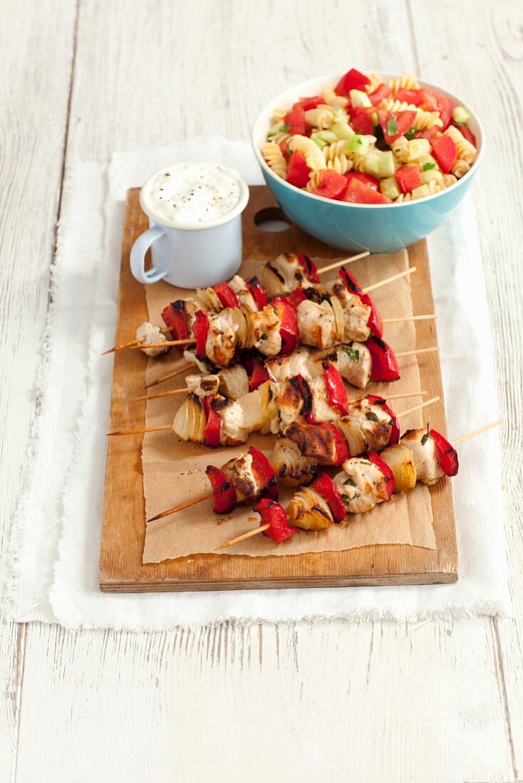 Chicken skewers with onions and pepper and a pasta salad with tomatoes and cucumber