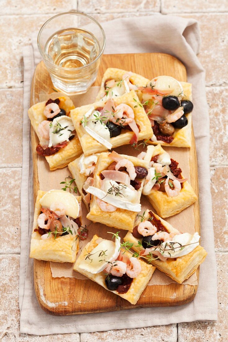 Mini-Torteletts mit Oliven, getrockneten Tomaten, Garnelen, Ziegenkäse und Schinken