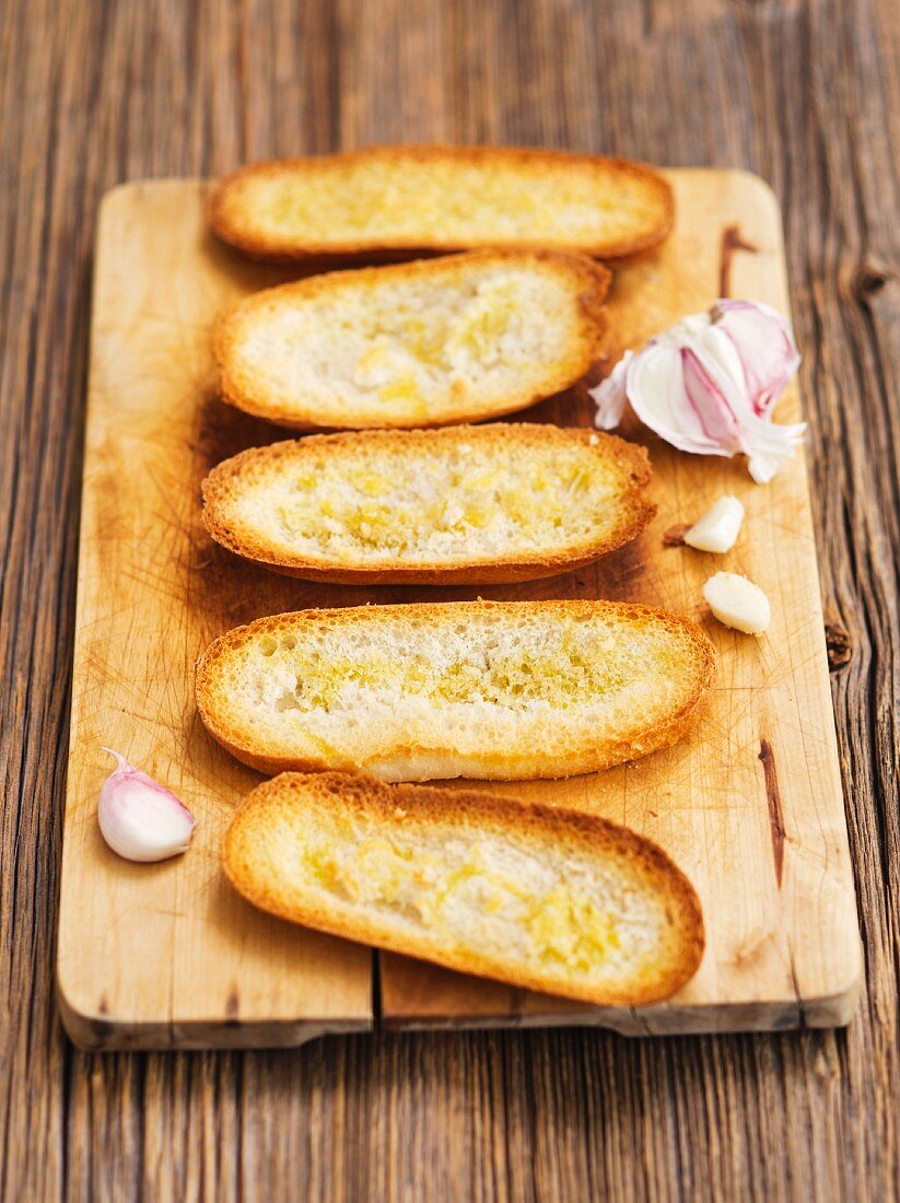 Röstbrote mit Knoblauch auf Schneidebrett