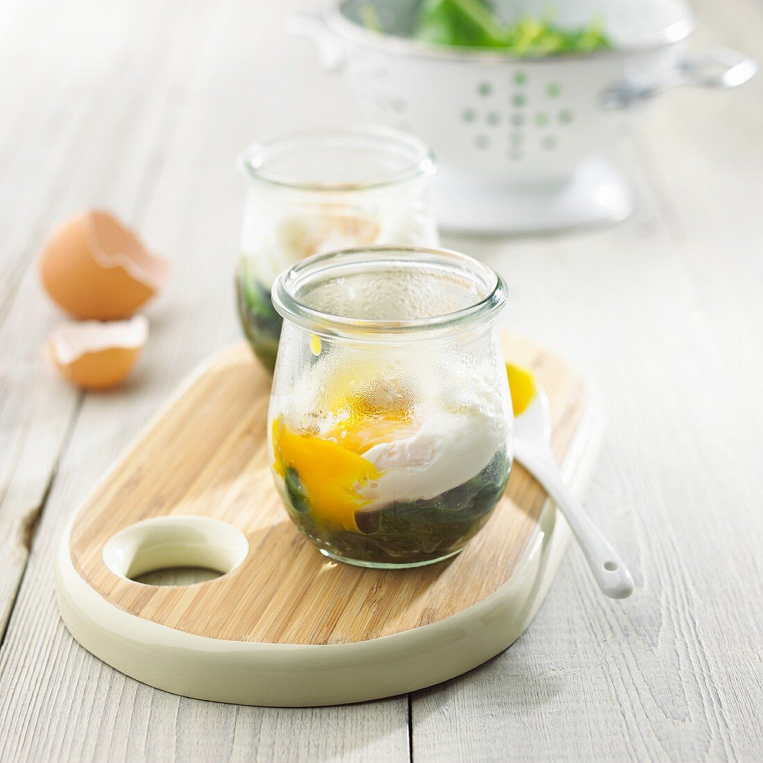 Poached eggs in glasses with spinach