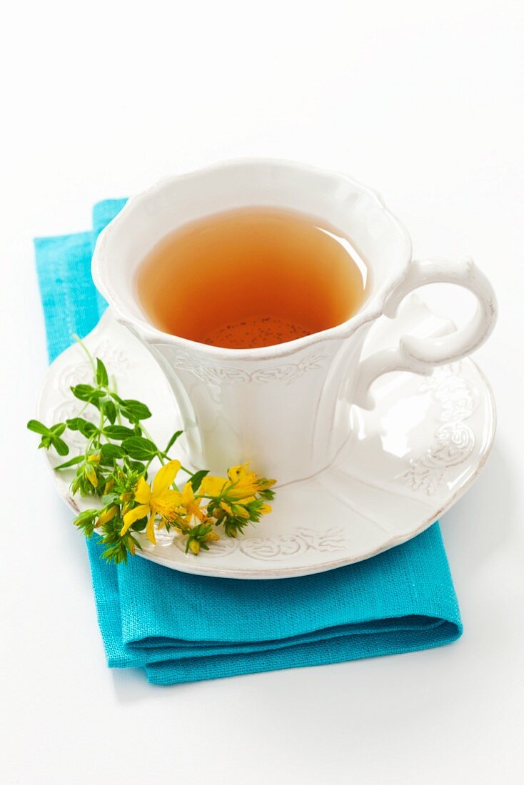 A cup of St. John's Wort tea and flowering St. John's Wort