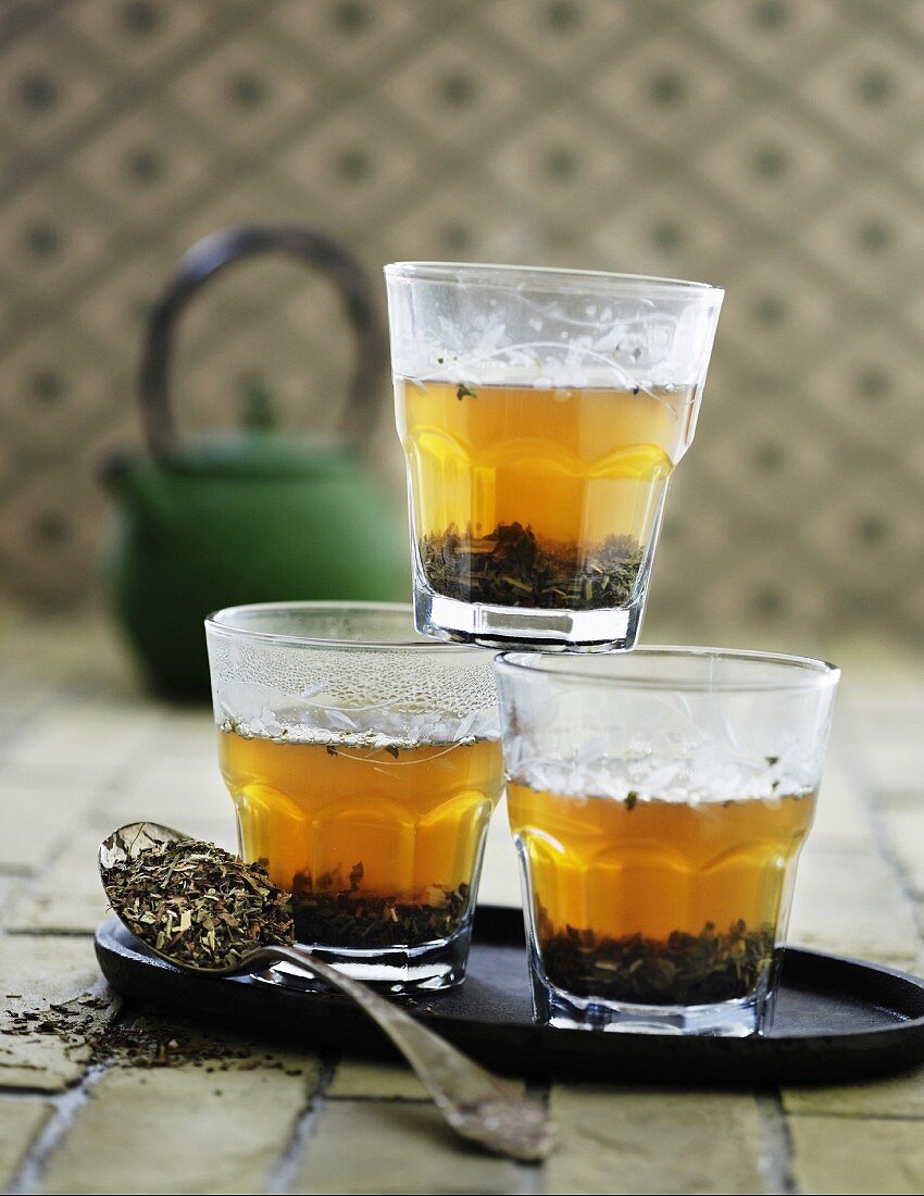 Three glasses of green tea and tea leaves