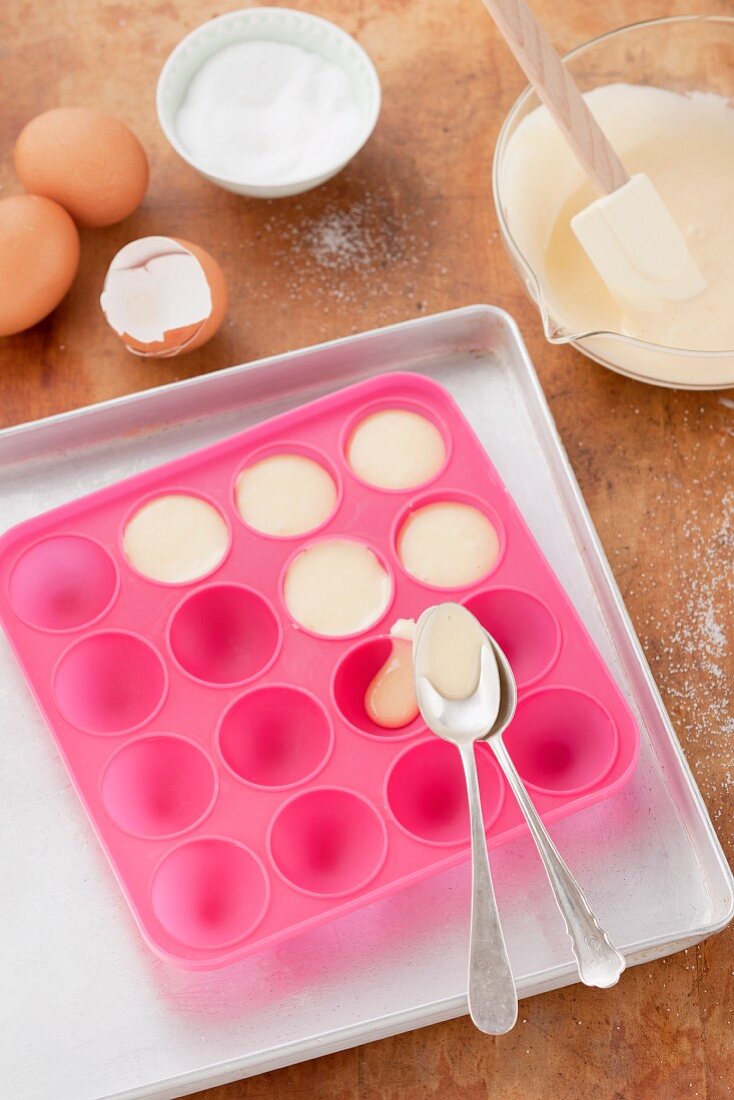 Cake mixture being spooned into a mould for cake pops