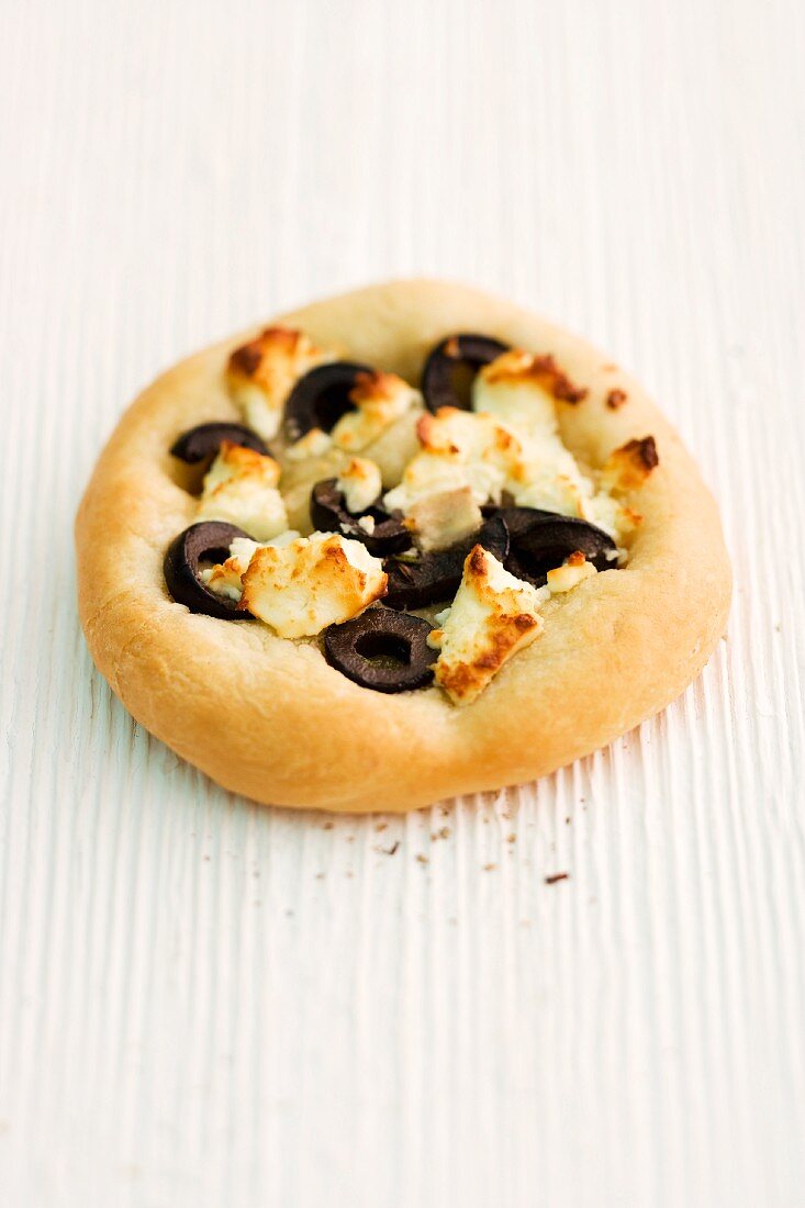 Focaccia with olives and sheep's cheese on a wooden surface