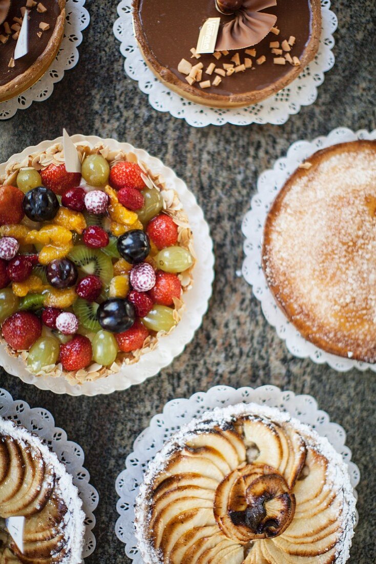 Fruit cake, chocolate cake, apple cake and lemon cake on a table