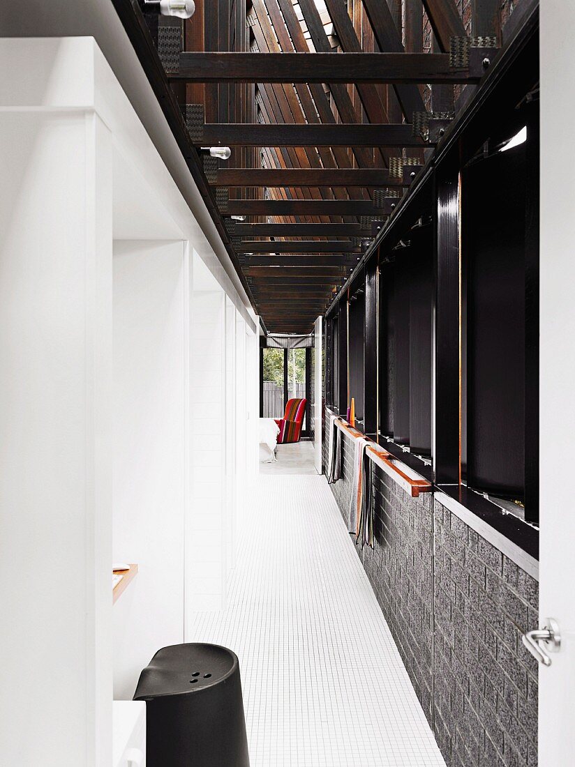 White tiled hallway with strip of windows on right and row of niches on left, one in foreground used as small office area