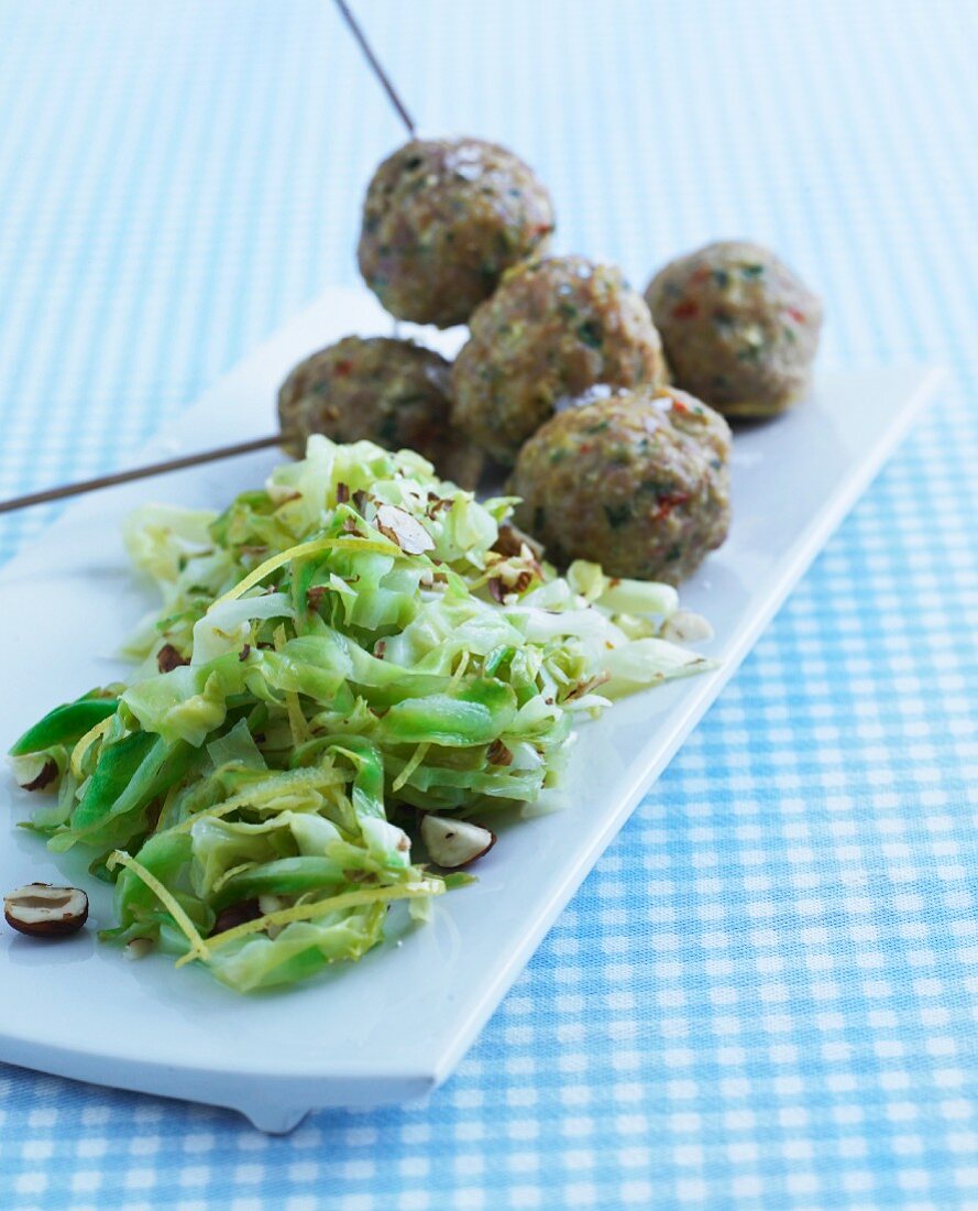 Cabbage salad with hazelnuts served with meatballs on sticks