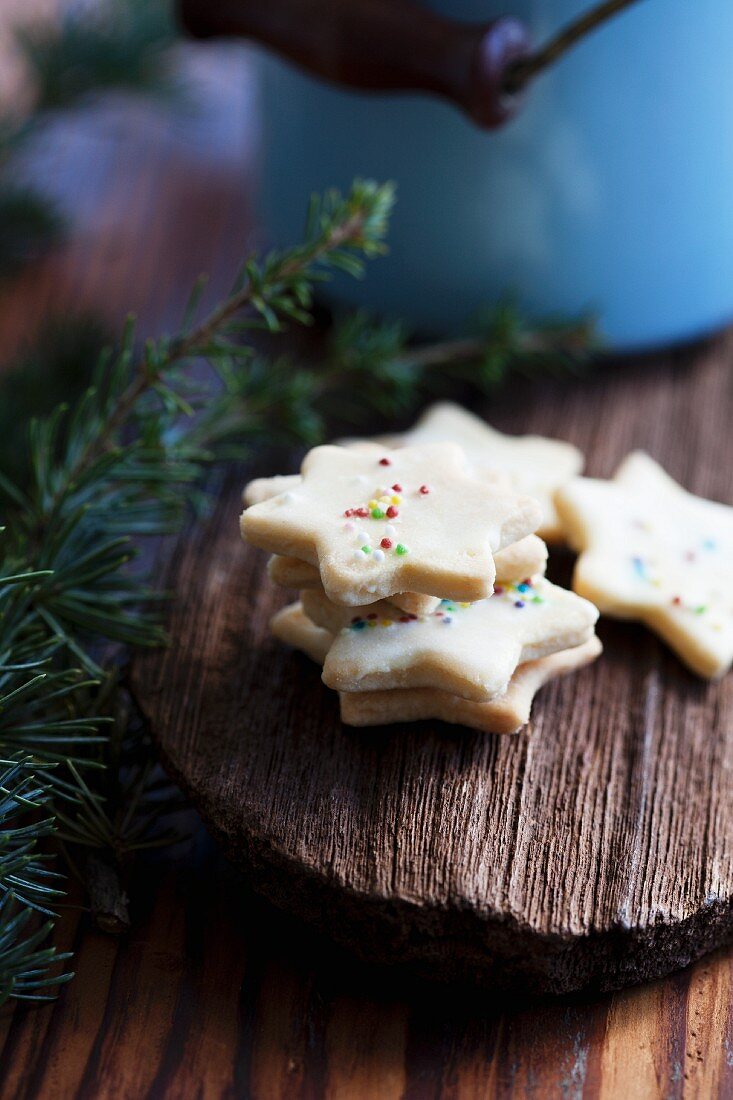 Butter biscuits decorated with coloured sprinkles on a piece of wood