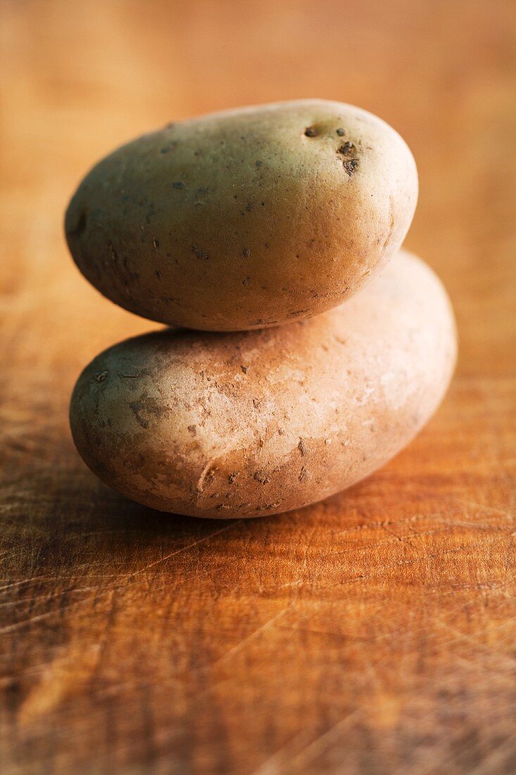 Two Marabel potatoes on a wooden surface