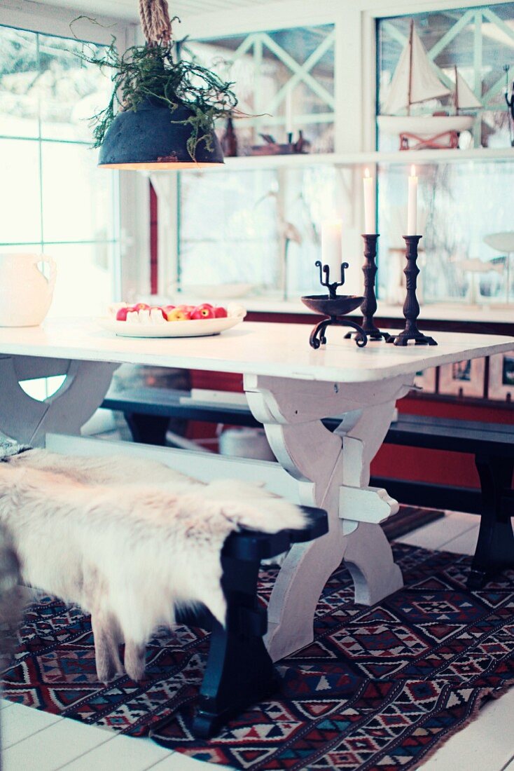 Essplatz in skandinavischer Landhausromantik mit rustikalem Esstisch und Fell auf einer Sitzbank
