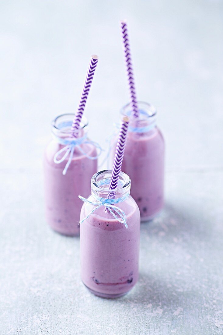 Three blueberry yoghurt smoothies in glass bottles