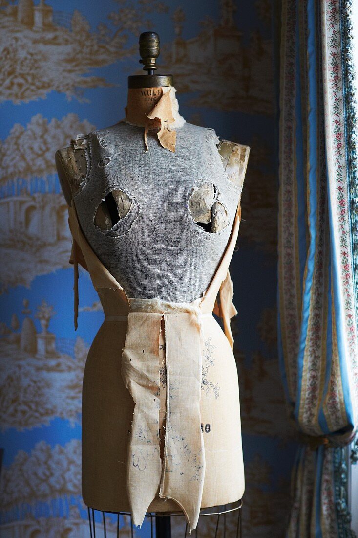 Old tailors' dummy in front of toil de jouy wallpaper in elegant, country-house interior