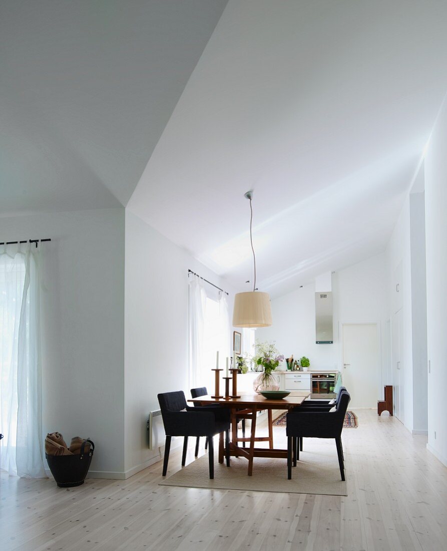 Dining area with upholstered chairs on wooden floor in open-plan, minimalist interior