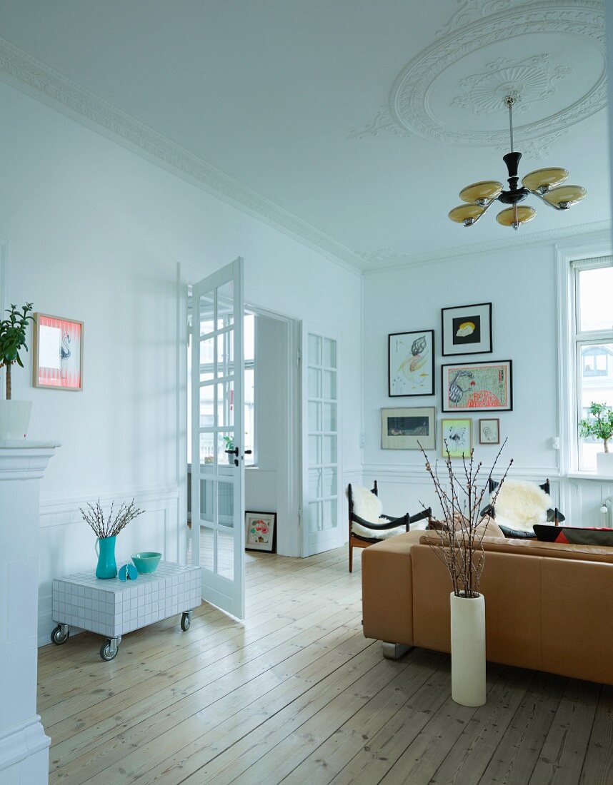 Living room with rustic flair, Art Deco pendant lamp, stucco ceiling, sofa, armchairs and open double doors to one side