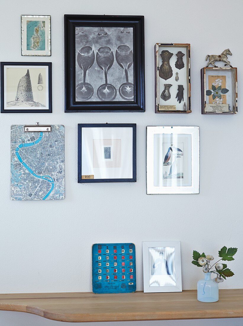 Frames pictures on wall above wooden shelf