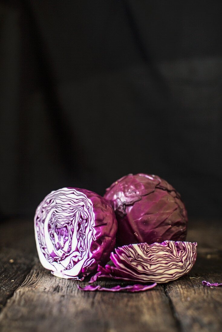 Red cabbage, whole and sliced, on a wooden surface