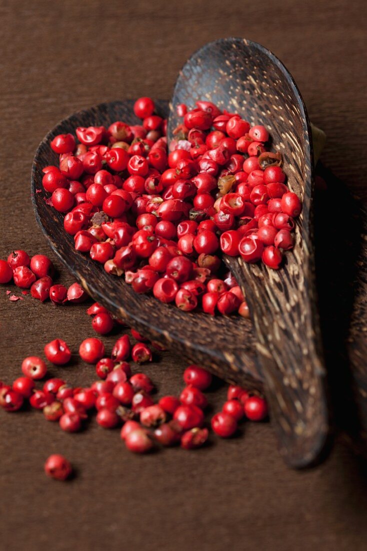 Pink peppercorns in a wooden dish with a spoon