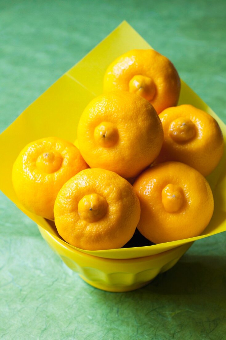 Bergamot lemons in a bowl lined with yellow paper