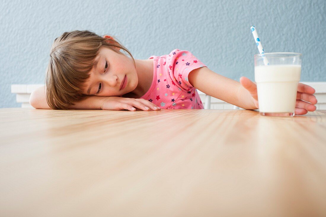 Müdes Mädchen mit einem Glas Milch
