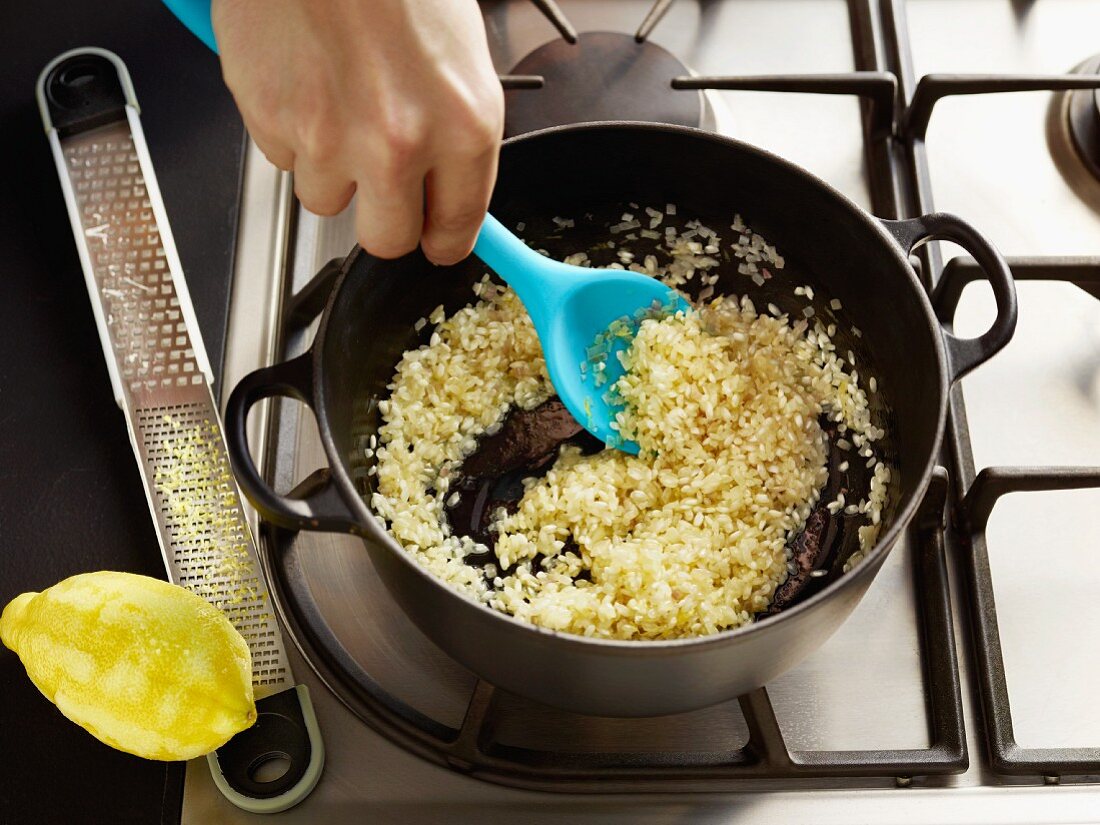 Risotto rice being fried in a pot with lemon zest