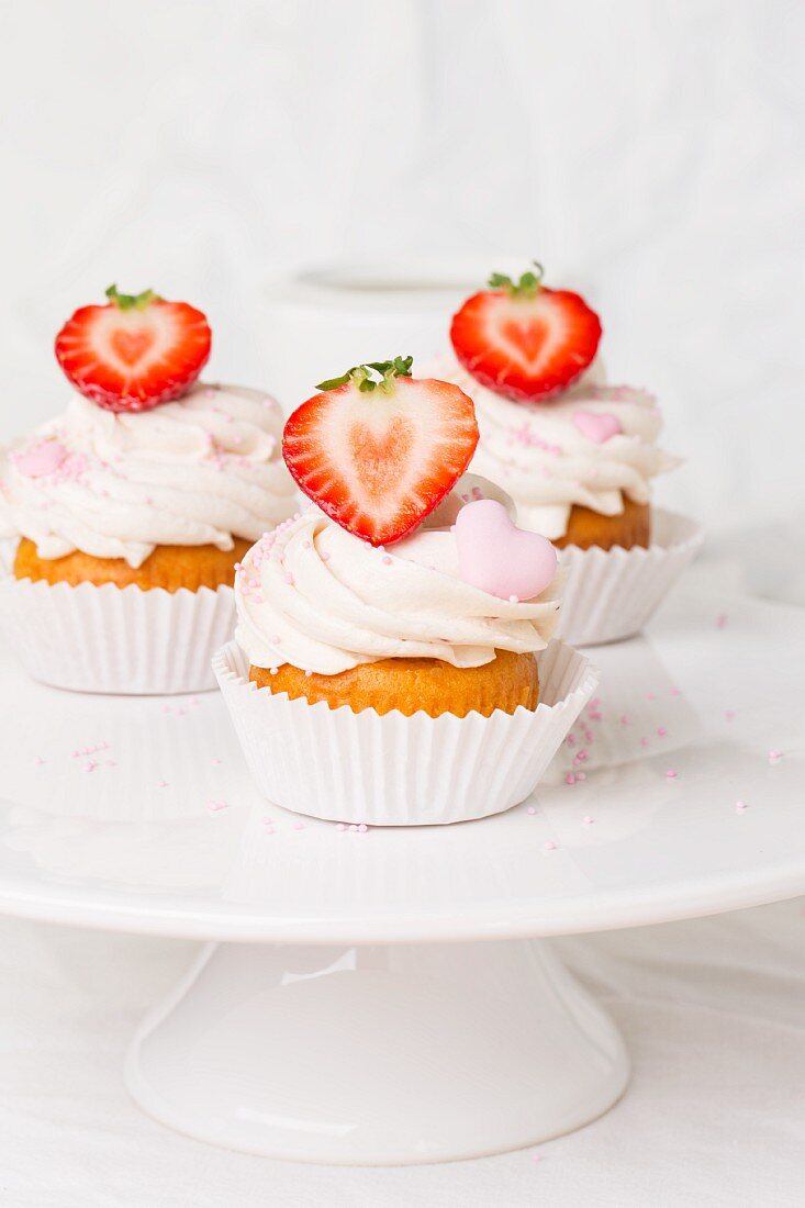 Drei Erdbeer-Cupcakes auf einer Tortenplatte