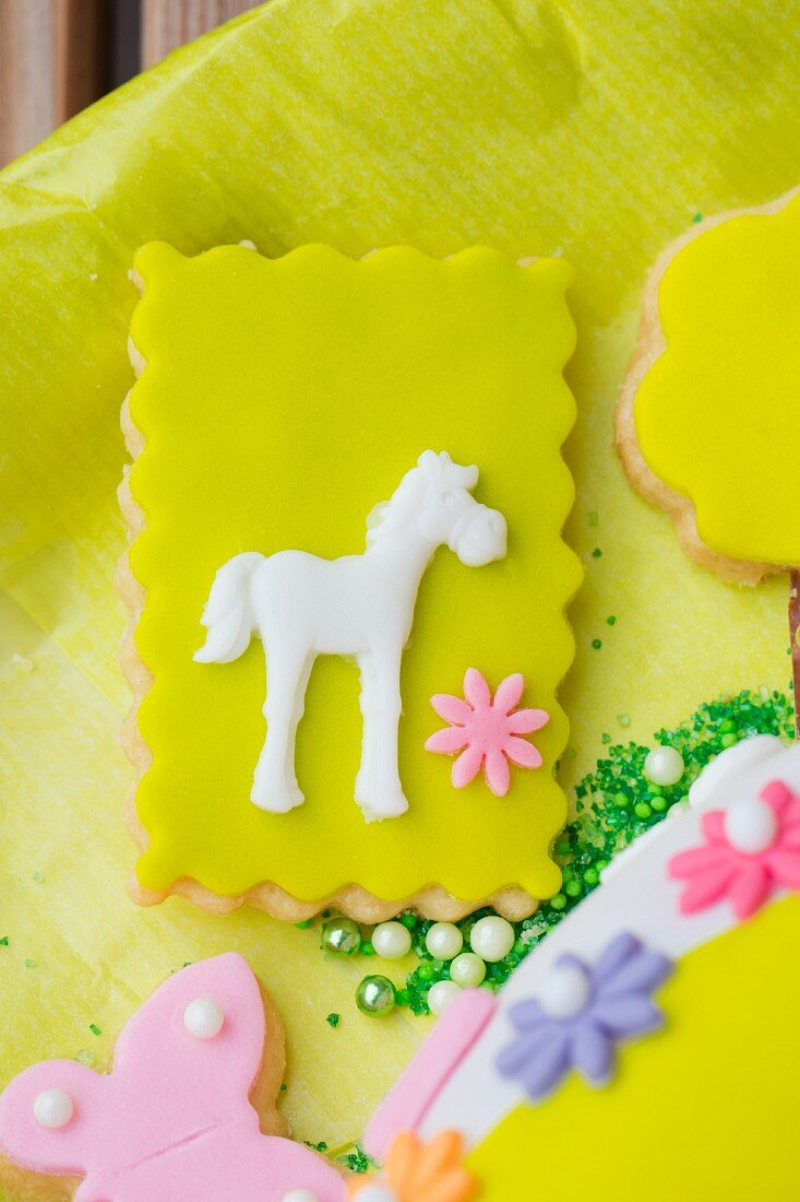 Shortcrust biscuits decorated with green fondant icing, flowers and a horse