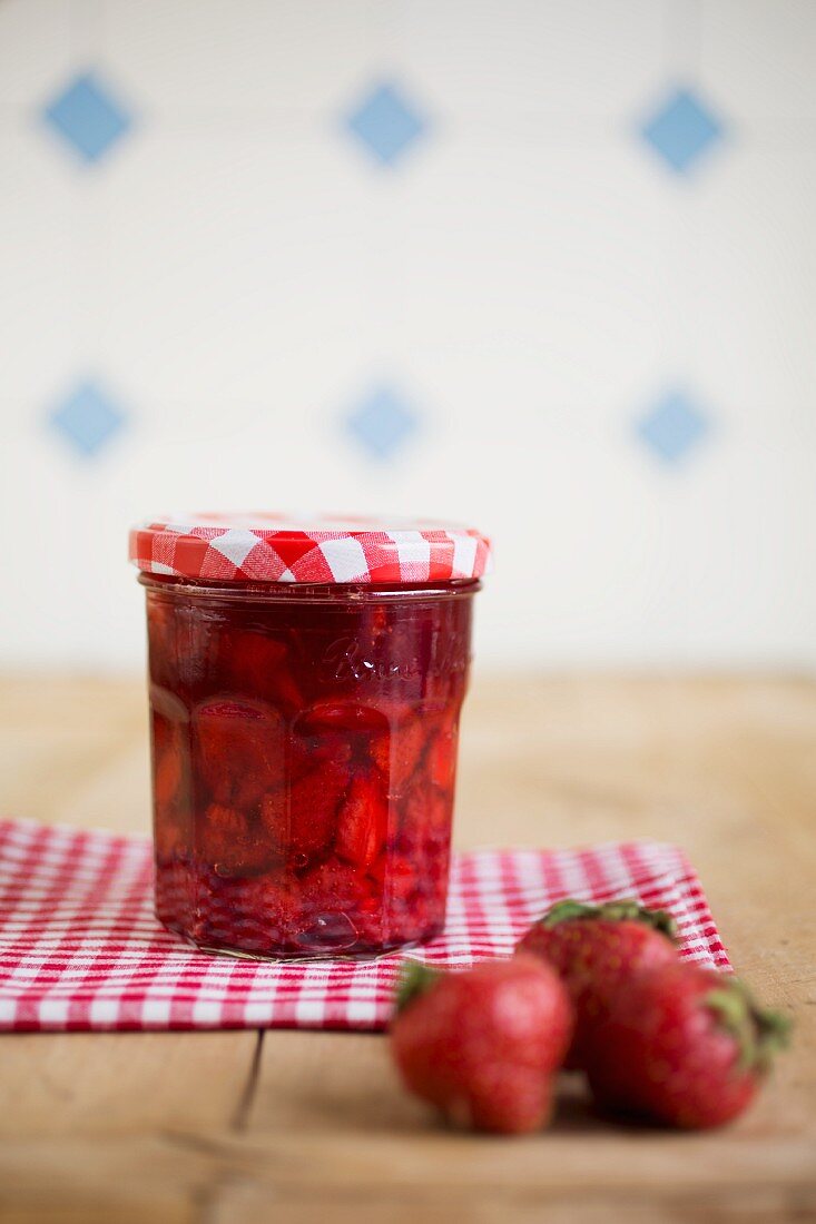 Ein Glas Erdbeermarmelade und frische Erdbeeren