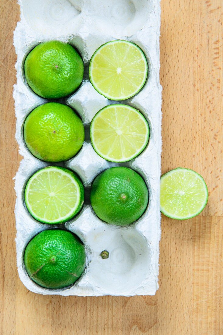 Limes, wholes and halved, in an egg box