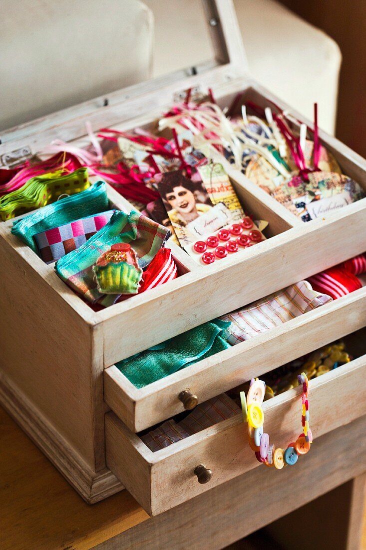 Paper gift tabs and colourful ribbons in small wooden case with open drawers