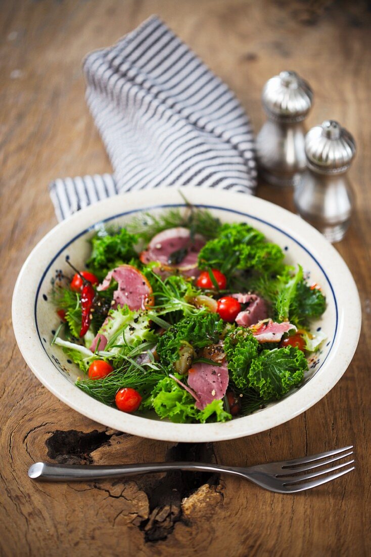 A green kale salad with goose breast and cherry tomatoes
