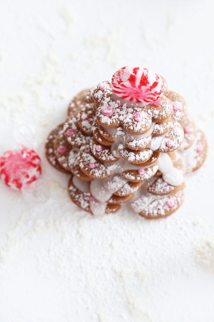 A gingerbread biscuit Christmas tree decorated with icing sugar and peppermint bonbons