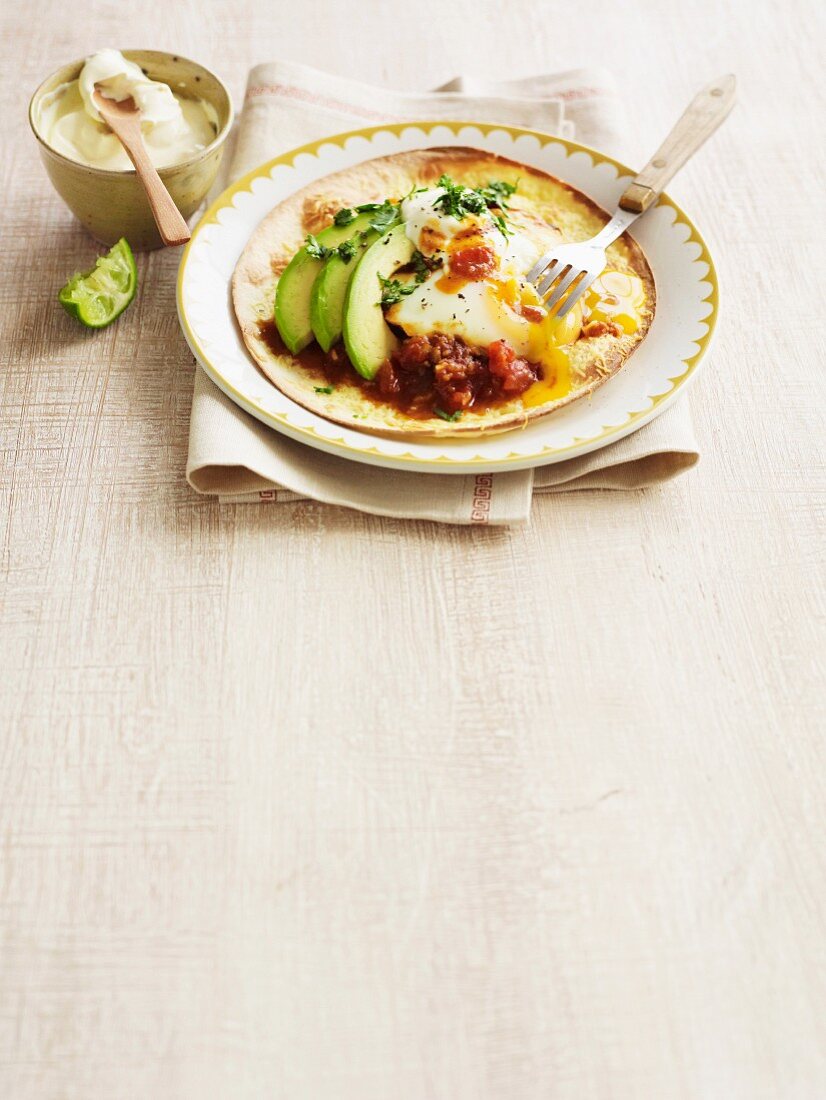 Tortilla mit Huevos Rancheros, Avocado, Tomatensauce und Sauerrahm (Mexiko)